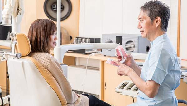 歯科医院で歯科医師と患者さまが説明を受けている写真