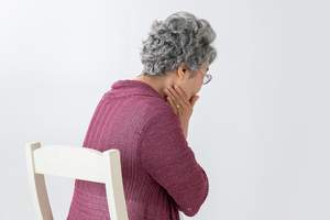 虫歯による痛みで顎付近を押さえている女性の写真