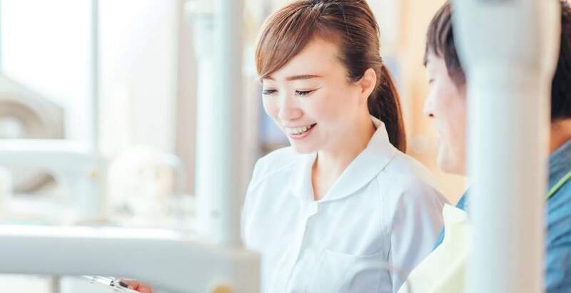 歯科医院でスタッフから矯正の説明を受けているイメージ