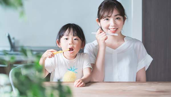 子どもと母親が一緒に歯磨きをしている写真
