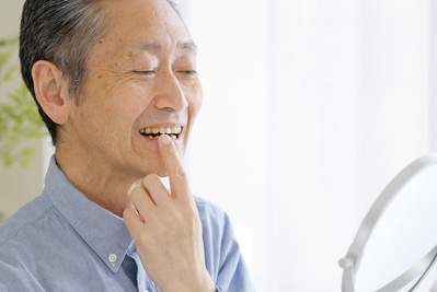 男性が鏡で歯を見ている写真