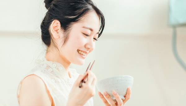 食事中の女性の写真。よく噛んで食事をすることで唾液の分泌が促進される。